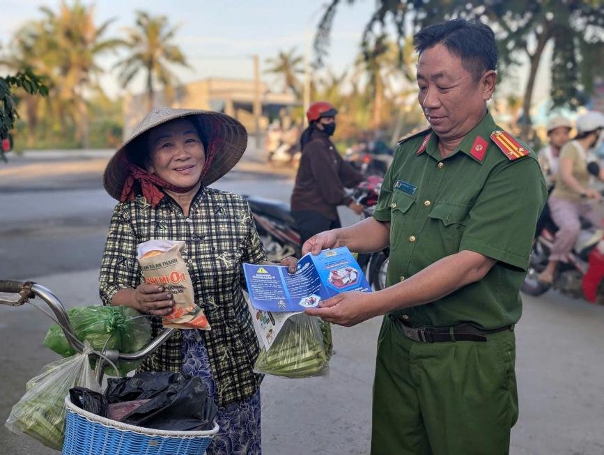 Cán bộ Công an xã An Thạnh trao tận tay ổ bánh mì 0 đồng cùng tờ rơi tuyên truyền pháp luật cho người dân trên địa bàn.